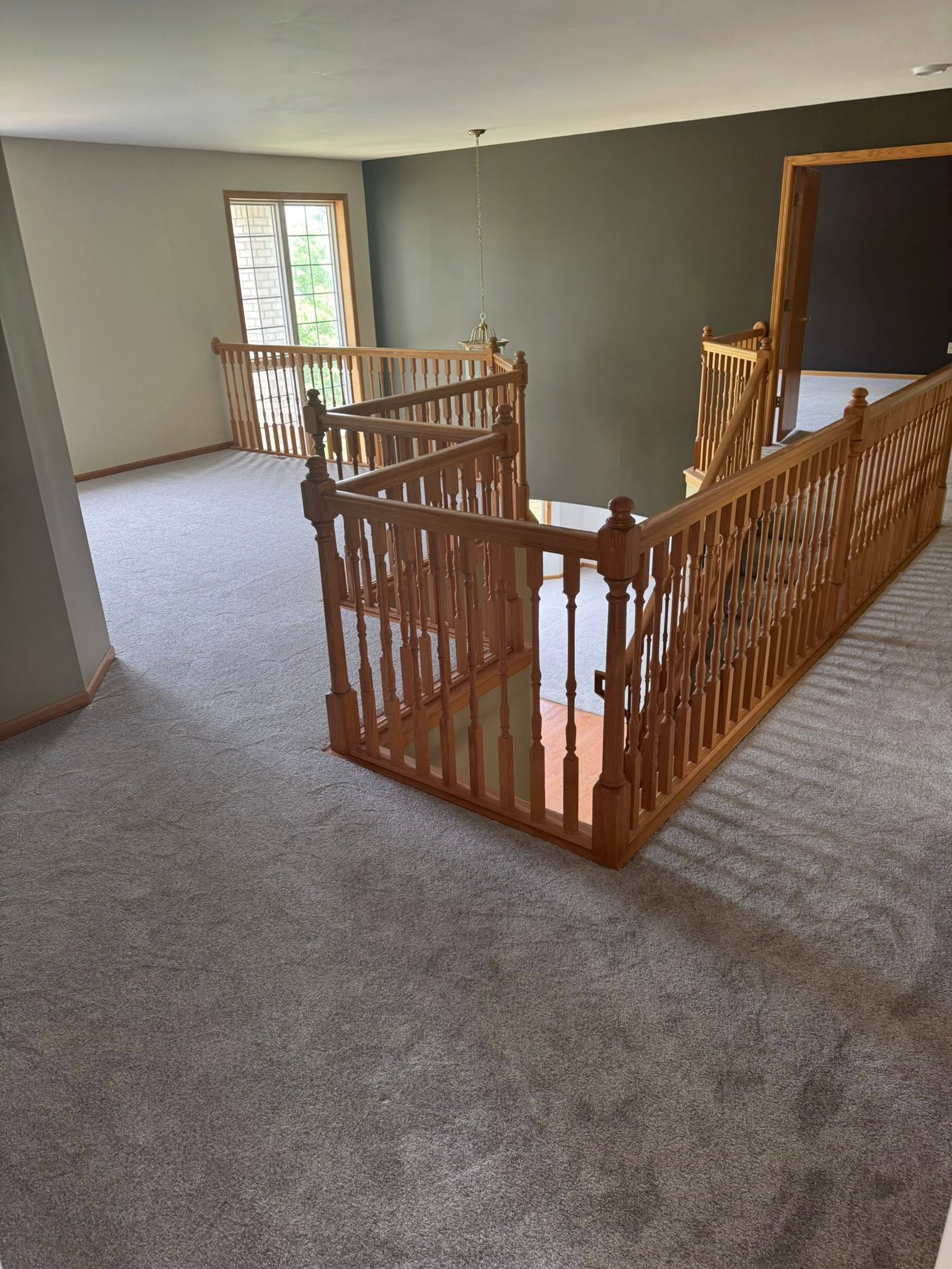 Plush gray carpet on an upstairs landing with oak railings